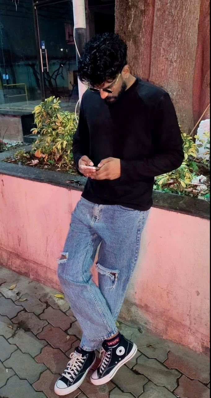 Street style in black sweatshirt and ripped denim at dusk